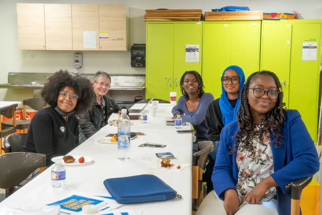 Five people sitting at a table smiling.